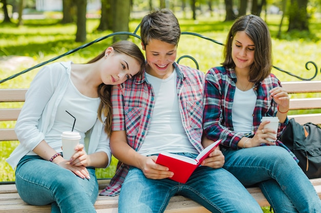 Meninas com homem e livro no banco