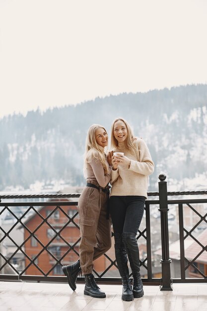 Meninas com roupas leves. Café de inverno na varanda. Mulheres felizes juntas.