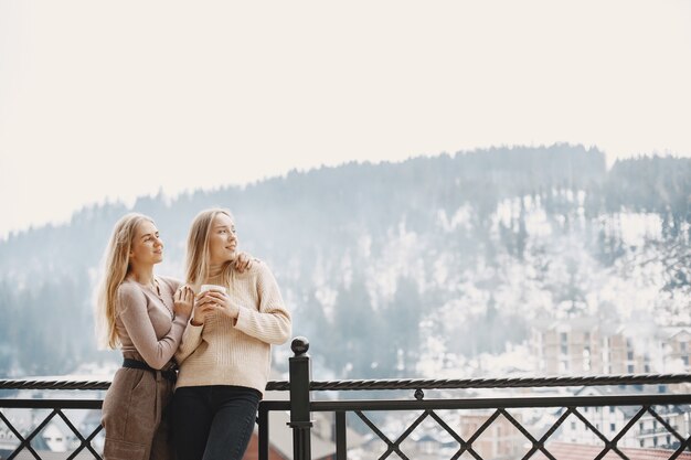 Meninas com roupas leves. Café de inverno na varanda. Mulheres felizes juntas.