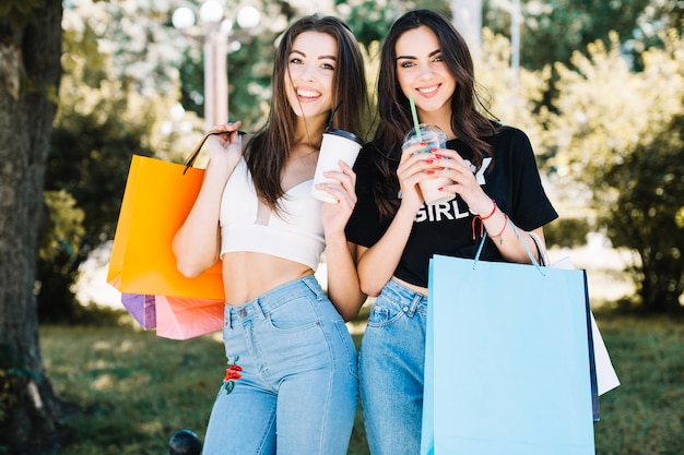 Foto grátis meninas com xícaras de café e sacolas de compras