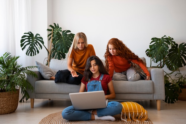 Foto grátis meninas de tiro completo com laptop dentro de casa