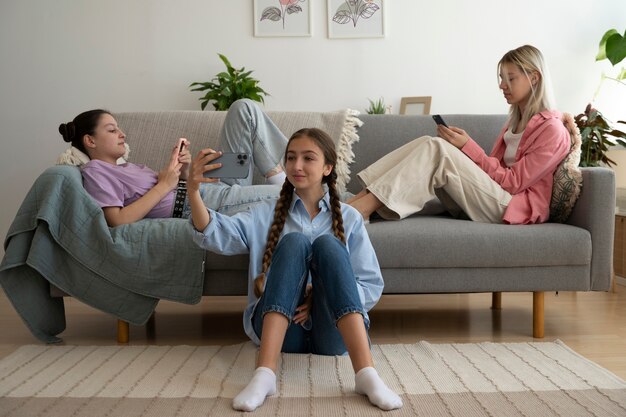 Meninas de tiro completo com smartphones em casa