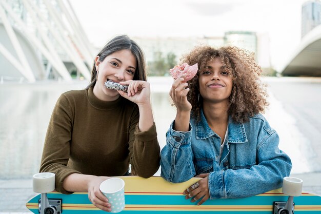 Meninas de tiro médio comendo rosquinhas