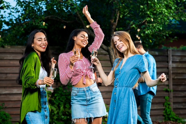 Meninas de vista frontal com bebidas dançando