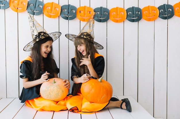 Meninas decorando abóboras de Halloween e rindo
