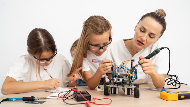 Meninas e professora fazendo experimentos científicos com um carro robótico