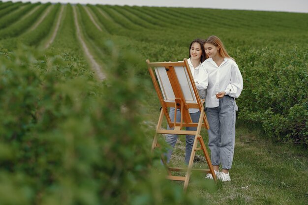 Meninas elegantes e bonitas, pintando em um campo