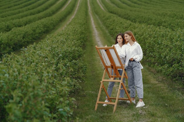 Meninas elegantes e bonitas, pintando em um campo