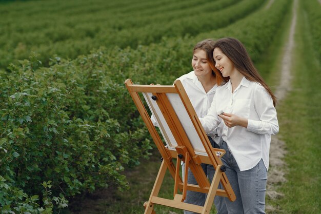 Meninas elegantes e bonitas, pintando em um campo