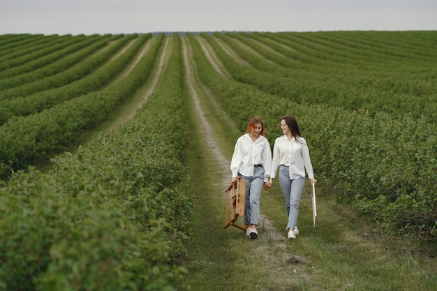 Meninas elegantes e bonitas, pintando em um campo