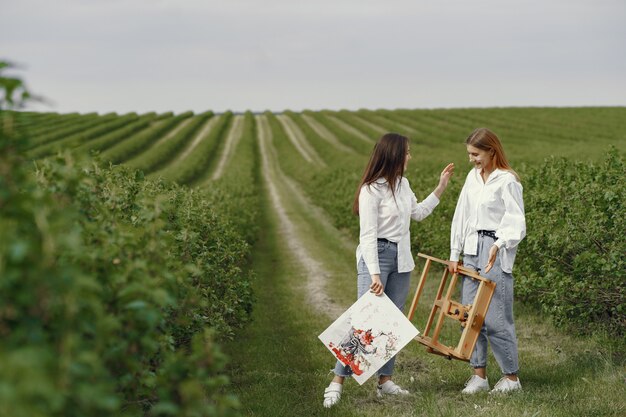 Meninas elegantes e bonitas, pintando em um campo