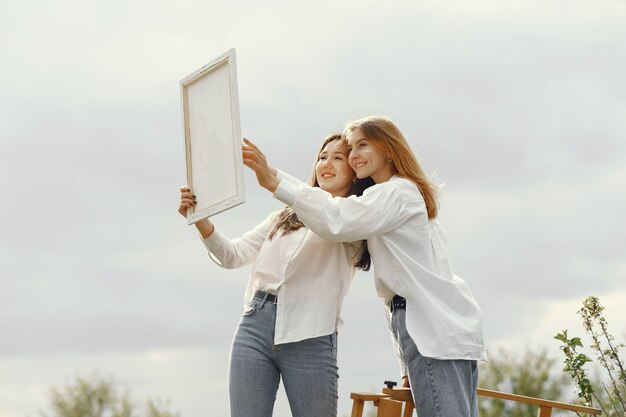 Meninas elegantes e bonitas, pintando em um campo