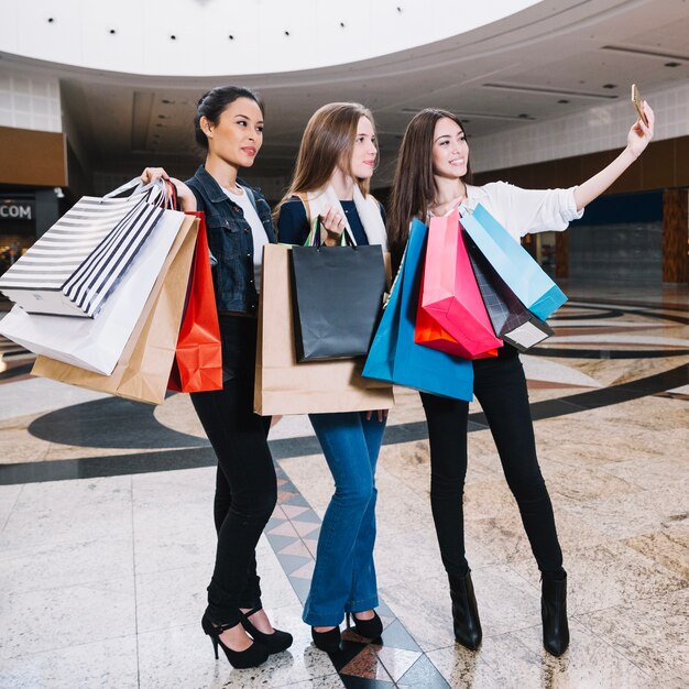Meninas elegantes levando selfie com bolsas