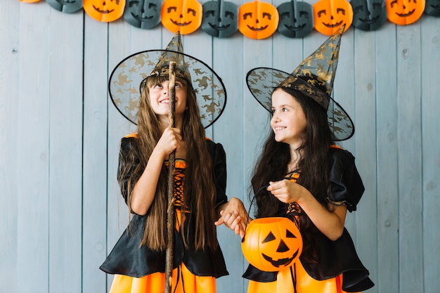 Meninas, em, dia das bruxas, trajes, segurando mão, sorrindo