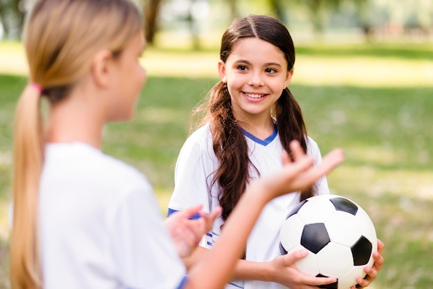 Meninas em equipamentos de futebol falando sobre a partida