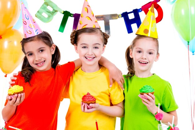 Meninas felizes e sorridentes segurando bolos coloridos - isolados em um fundo branco.