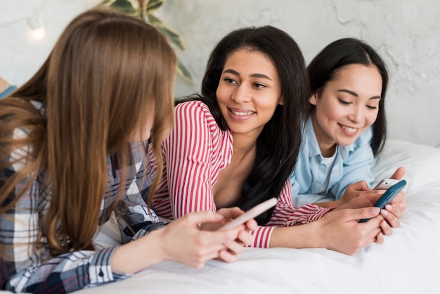 Meninas, mentindo cama, e, olhando telefone móvel