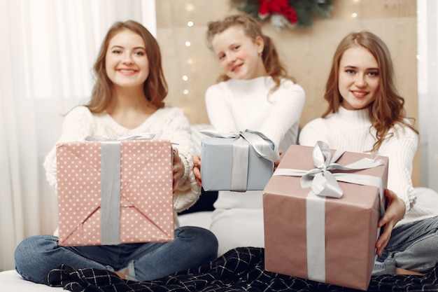 Foto grátis meninas sentadas na cama. mulheres com caixas de presente. amigos se preparando para o natal.