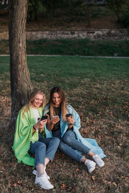 Meninas sentadas no parque ao lado de uma árvore