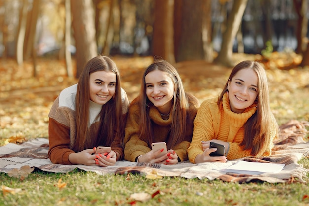 Meninas, sentado em um cobertor em um parque de outono