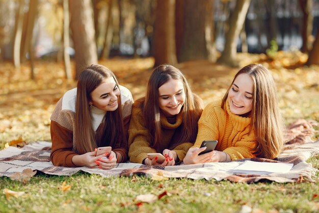 Meninas, sentado em um cobertor em um parque de outono