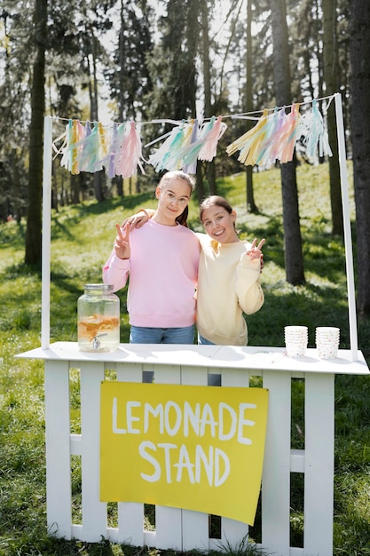 Meninas sorridentes de tiro completo com limonada