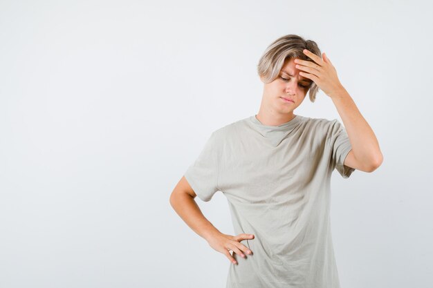 Menino adolescente com uma camiseta sofrendo de dor de cabeça e parecendo angustiado