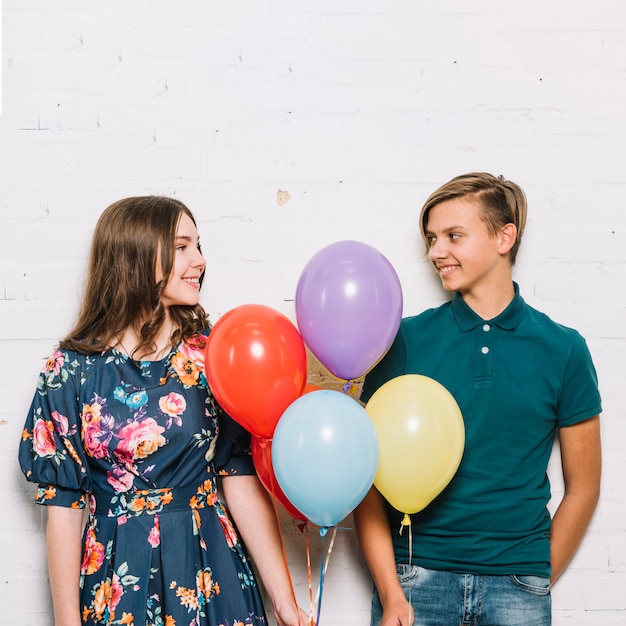 Menino adolescente, e, menina, segurando balões, em, mão, olhando um ao outro
