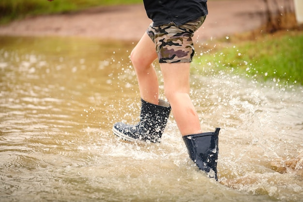 Foto grátis menino andando em um riacho inundado usando gumboots