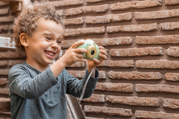 Foto grátis menino ao ar livre com o brinquedo da câmera