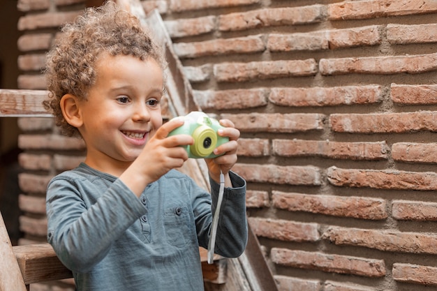 Foto grátis menino ao ar livre com o brinquedo da câmera