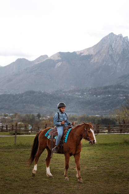 Foto grátis menino aprendendo a andar a cavalo