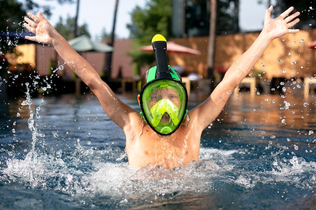 Menino aproveitando o dia na piscina com máscara de mergulho