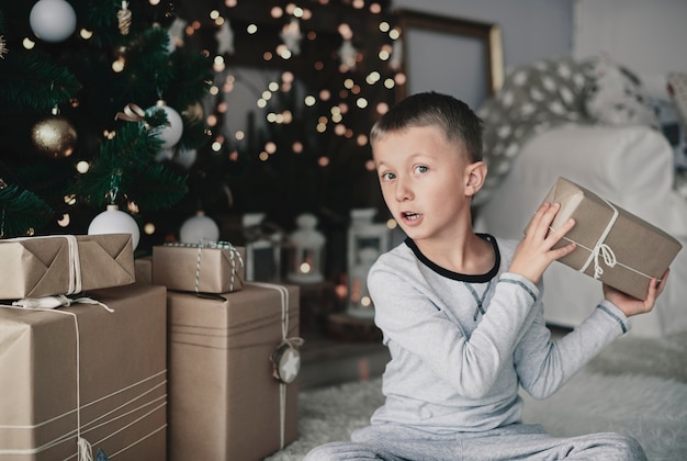 Menino arrumando presentes de natal ao lado da árvore de natal