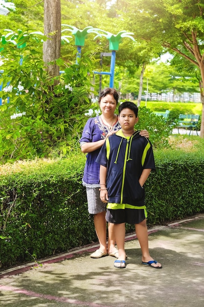 Menino asiático bonitinho com a mãe no jardim