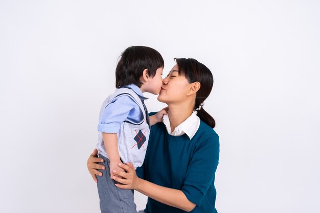 Menino asiático de retrato beijando sua mãe com amor