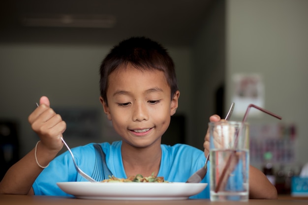 Menino asiático, menino, comendo alimentos saudáveis ​​na cantina ou na cafeteria.