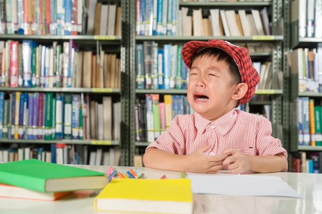 Menino asiático na escola da sala da biblioteca