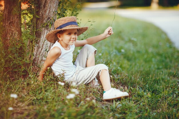 Menino bonitinho com um chapéu passando um tempo em um parque de verão