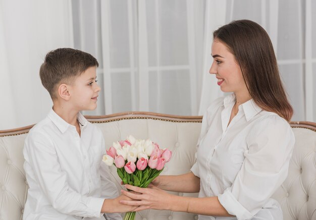 Menino bonitinho dando flores para sua mãe