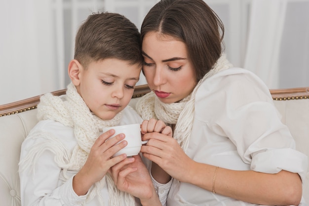 Menino bonitinho e mãe segurando uma xícara