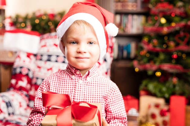 Menino bonito com presentes e um chapéu de Santa