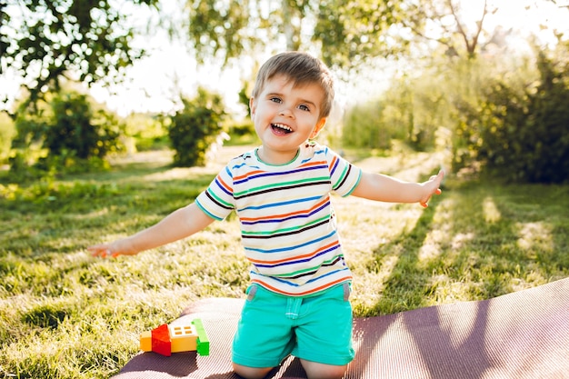 Menino bonito parece feliz no jardim de verão com sua casa de brinquedo.