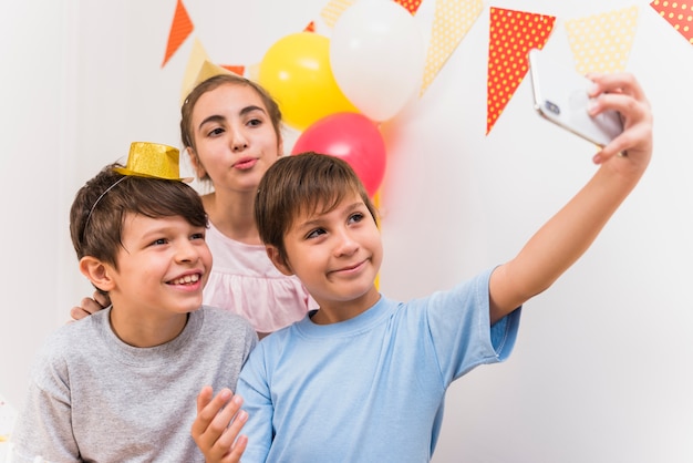 Menino bonito, tendo selfie com seus amigos no telefone inteligente