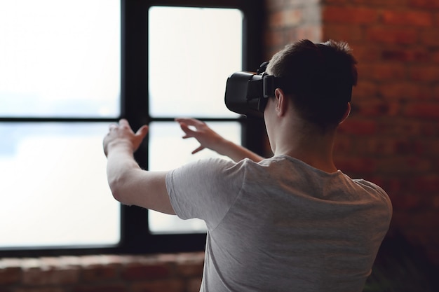 Menino brincando com fone de ouvido VR em casa