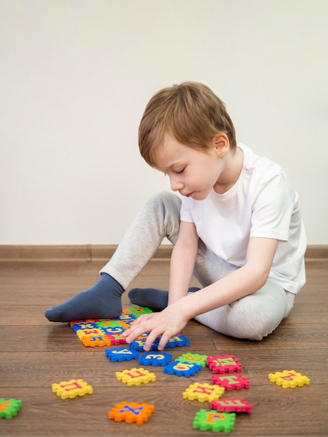 Menino brincando com o jogo do alfabeto dentro de casa