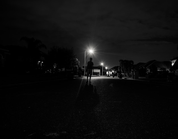 Menino caminhando sozinho à noite sob as luzes da rua