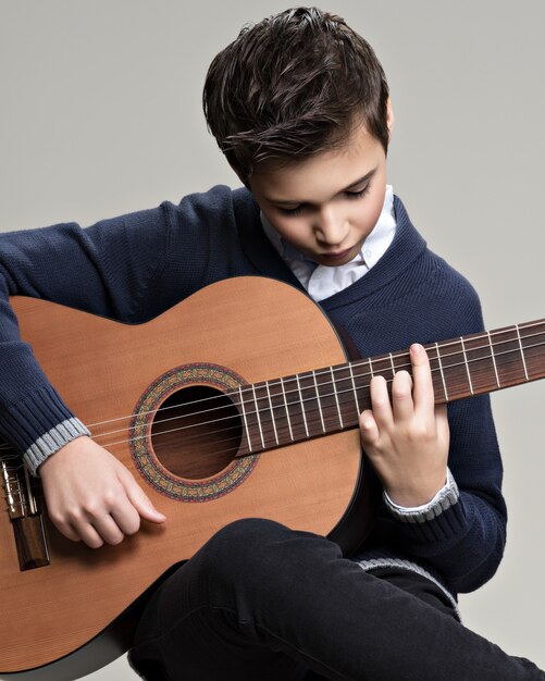 Menino caucasiano tocando violão.
