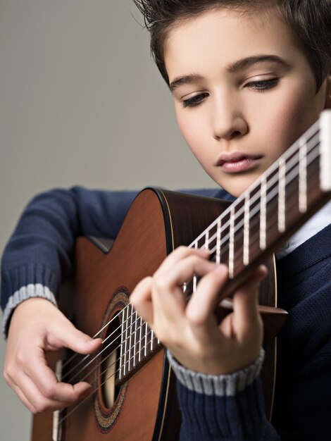 Menino caucasiano tocando violão.