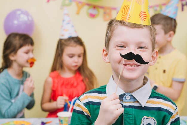 Menino com bigode de papel na festa de aniversário